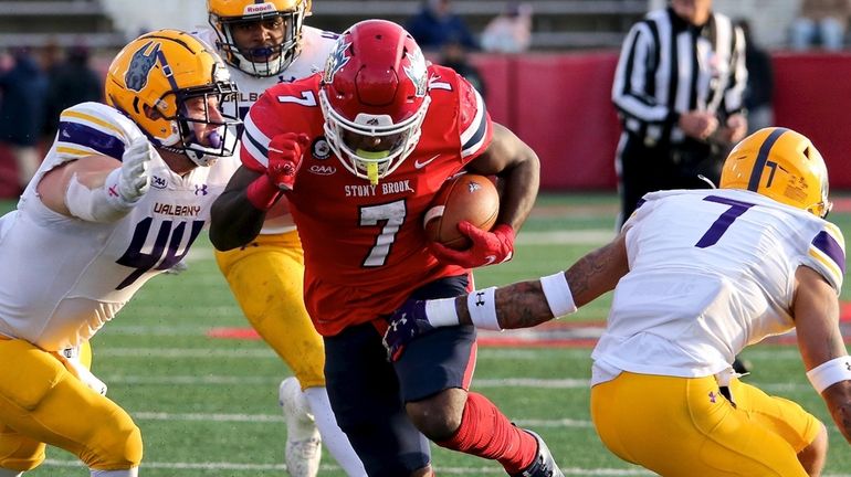 Stony Brook running back Ty Son Lawton runs between two Albany...