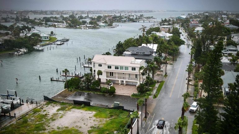 A driver negotiates a flooded street as Tropical Storm Debby...