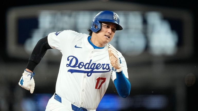 Los Angeles Dodgers designated hitter Shohei Ohtani rounds third on...