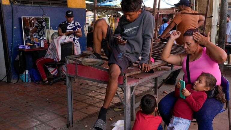 Carla Machado, right, waits with her children for her husband...