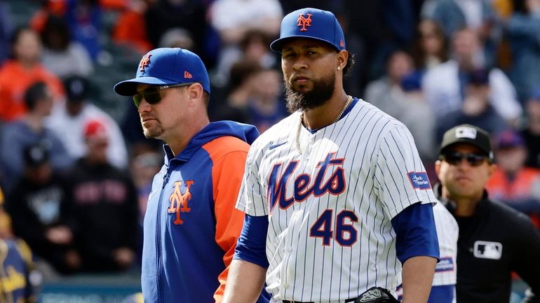 Yohan Ramirez and manager Carlos Mendoza of the Mets walk...