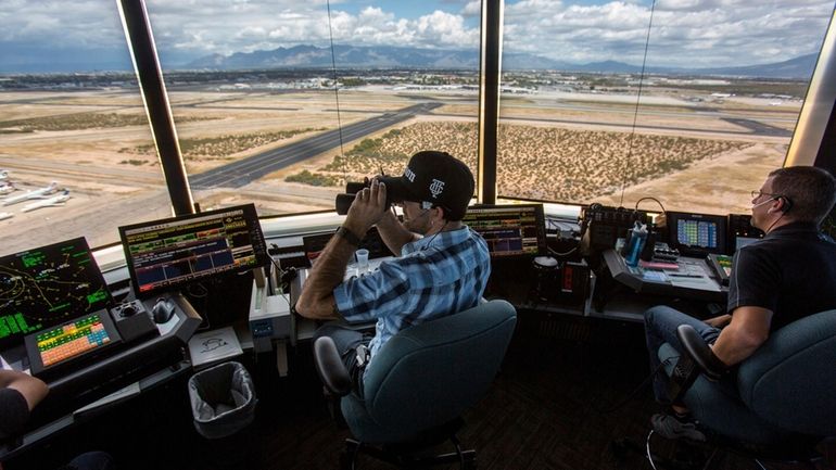 Air traffic controllers watch for traffic from the control tower...