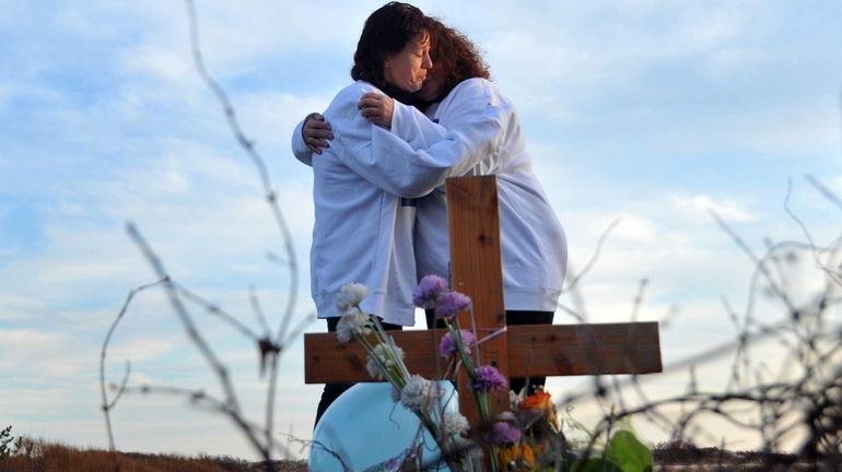 Lorraine Ela is comforted by her friend, Carrie Laroche, as...