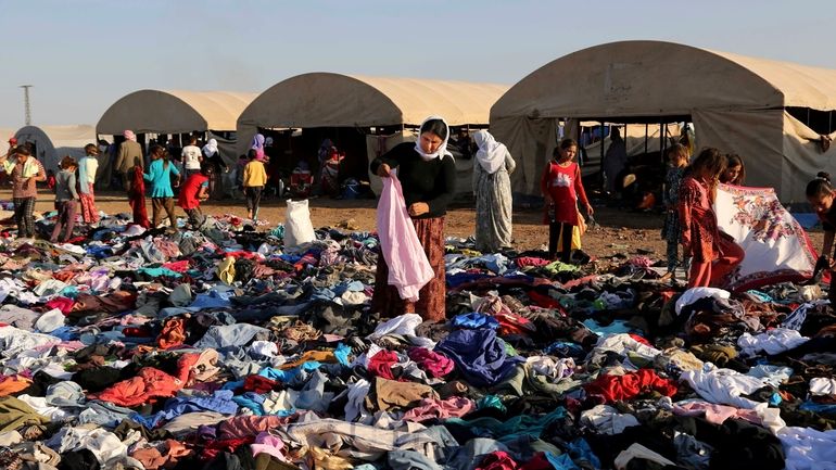 Displaced Iraqis from the Yazidi community look for clothes to...