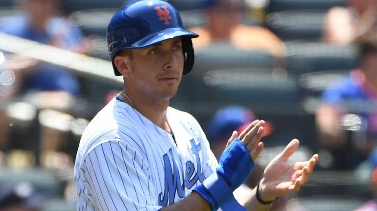 Mets third baseman T.J. Rivera reacts after he scores against...