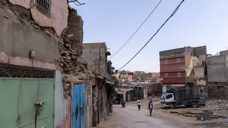 People walk past buildings which were affected by the 2023...