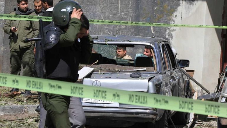 Syrian security forces walk through the destruction following two bombings...