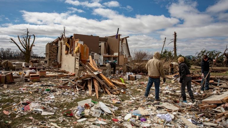 Family and neighbors look through debris on Ed Whestine's farm...