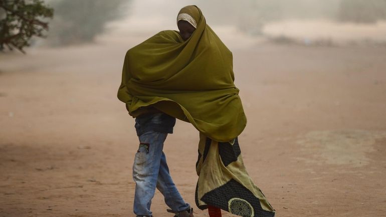 Somali refugee children cover themselves as a dust storm moves...