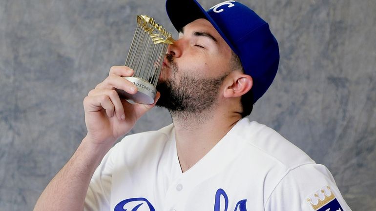 Kansas City Royals' Eric Hosmer kisses a replica World Series...