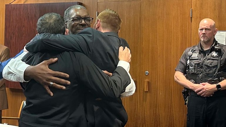 Three security guards hug after a jury found them not...