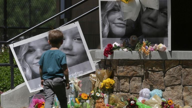 A boy looks at a memorial for Tylee Ryan and...