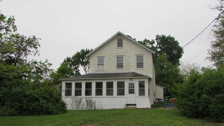 This antique Levittown Colonial has a large enclosed front porch....