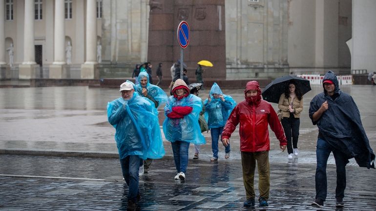 People cross a street during a rainy day, in Vilnius,...