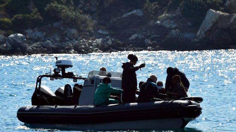 Survivors sit on a vessel after a boat carrying migrants...