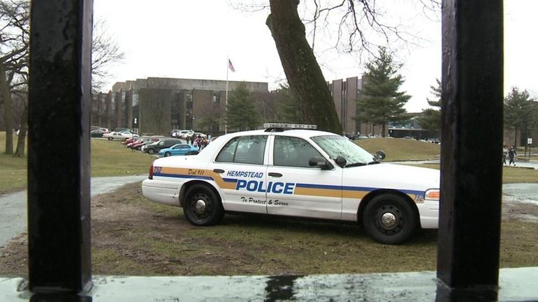 A Hempstead police car waits outside Hempstead High School as...