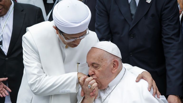 Pope Francis, right, kisses the right hand of the Grand...