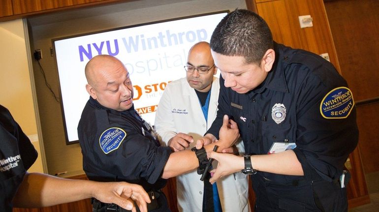 Trauma surgeon Dr. Fahd Ali, center, watches security officers Luis...