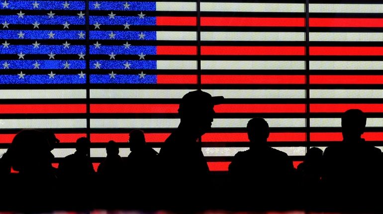 People gather near an electronic display of an American flag...