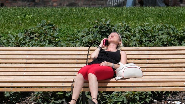 A woman sunbathes in a park in Milan, Italy, Tuesday,...