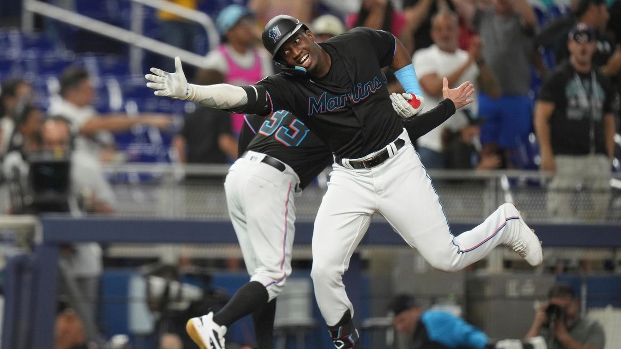 Jon Jay first base coach of the Miami Marlins holds his hat to his