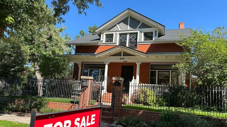 A for sale sign stands outside a home on the...