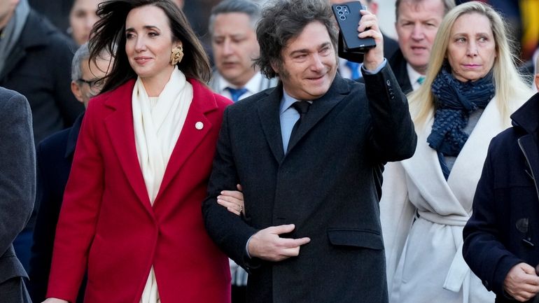 Argentine President Javier Milei walks arm-in-arm with Vice President Victoria...