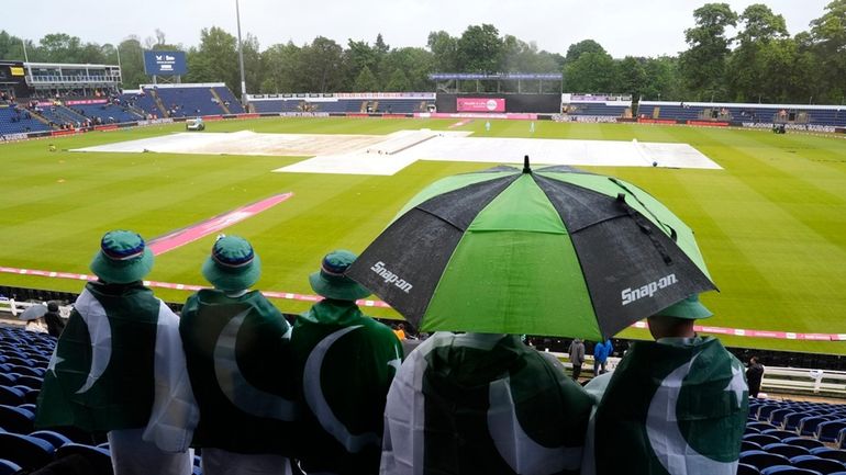 Fans in the stands shelter from the rain under umbrellas...