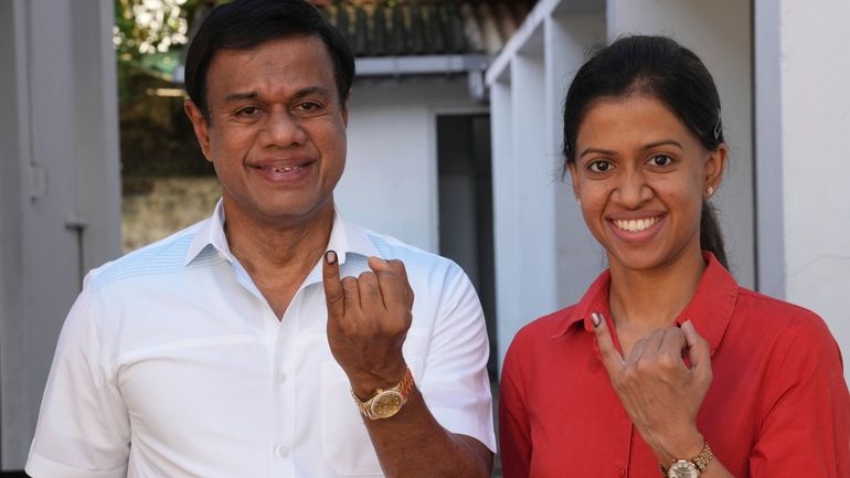 Sri Lankan show their index fingers marked with an indelible...