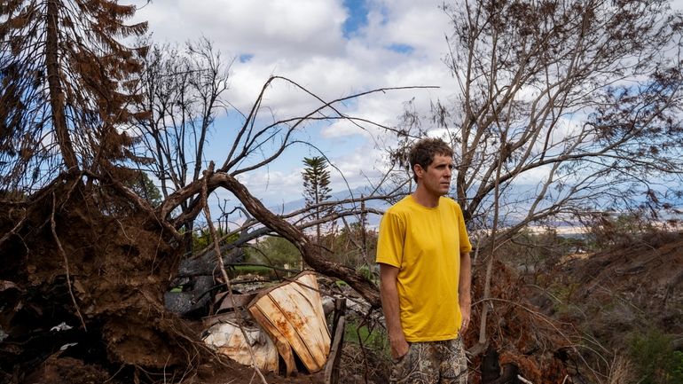 Kyle Ellison stands in front of a fallen tree on...