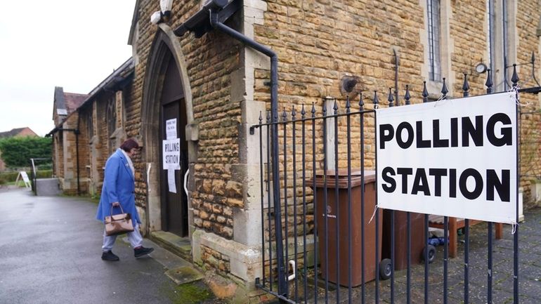 People arrive at St Peter's Church Hall as voting gets...