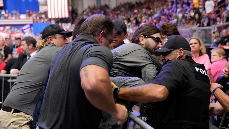 Police remove a man, center with sunglasses, who had climbed...