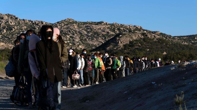 Chinese migrants wait to be processed after crossing the border...