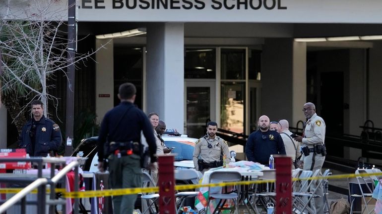 Las Vegas police stand near the scene of a shooting...