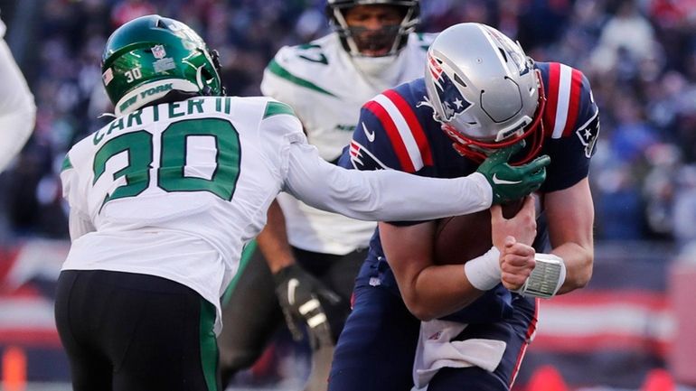 Patriots quarterback Mac Jones, right, is tackled by Jets cornerback Michael...