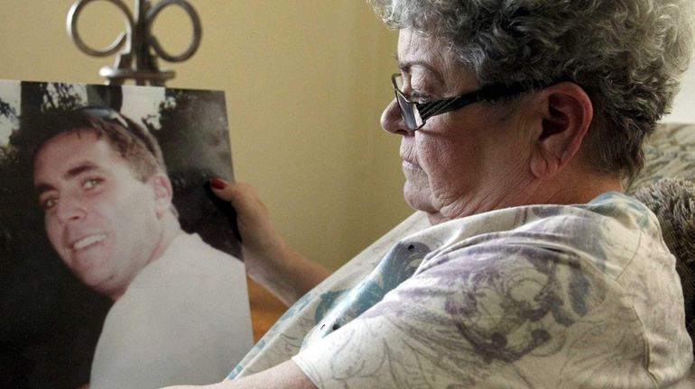 Marge Gleeson, holding a photo of her son John, who...