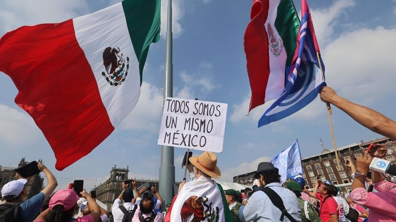 A person holds a sign that reads "we are all...