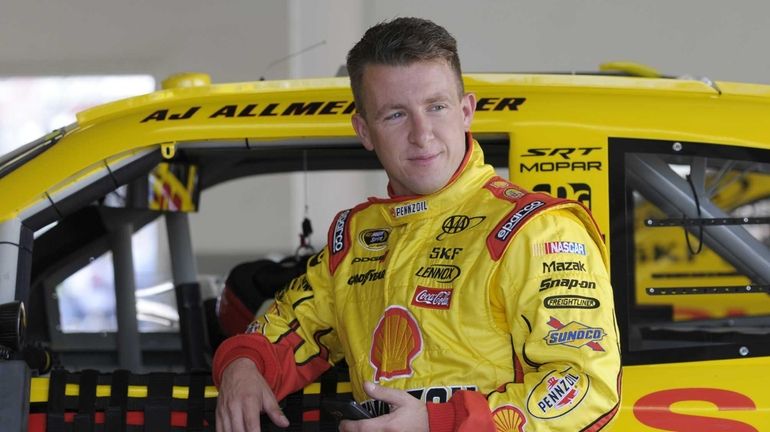 AJ Allmendinger leans against his car in the garage area...