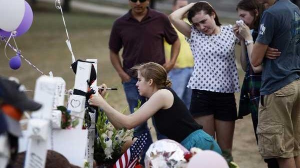 Mourners gather at a makeshift memorial across the street from...