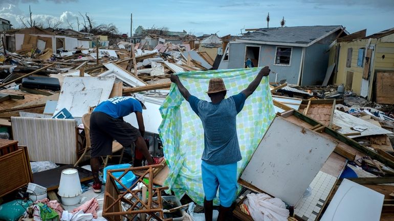 Immigrants from Haiti recover their belongings from the rubble in...