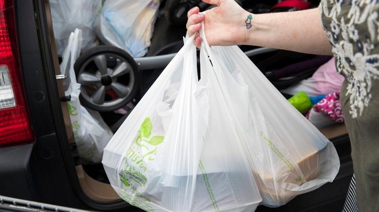 A woman loads her car with groceries from the Stop...