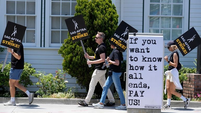 Picketers carry signs outside Amazon Studios in Culver City, Calif....