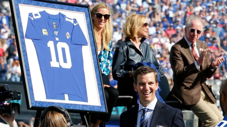 Former Giants quarterback Eli Manning looks on during his jersey...