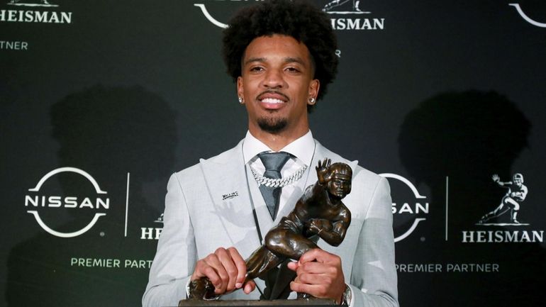 Heisman winner Jayden Daniels of LSU holds his trophy at...