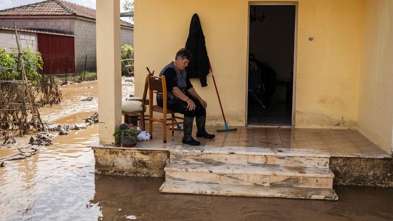 A woman takes a break from cleaning her flooded house...