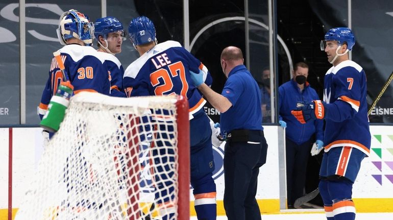 Anders Lee of the Islanders is assisted off the ice...