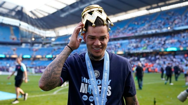 Manchester City's goalkeeper Ederson celebrates with the Premier League trophy...