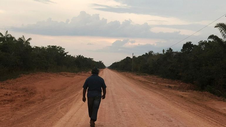 A man walks down an unpaved stretch of highway BR-319...