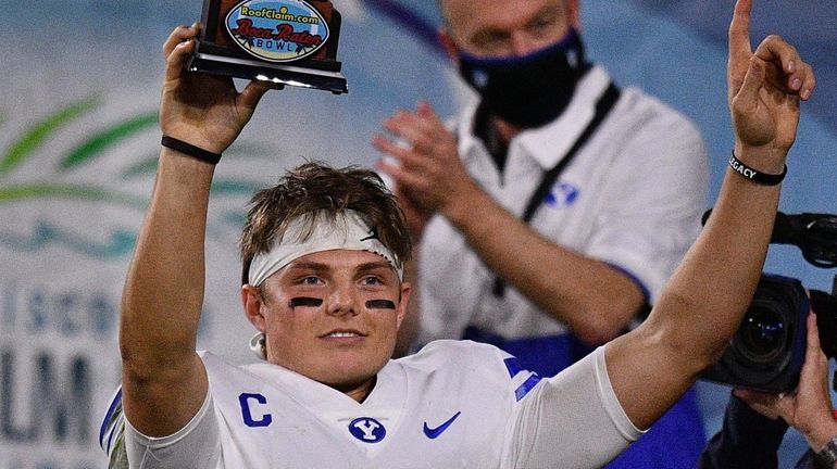 BYU's Zach Wilson lifts the MVP Trophy after beating Central...