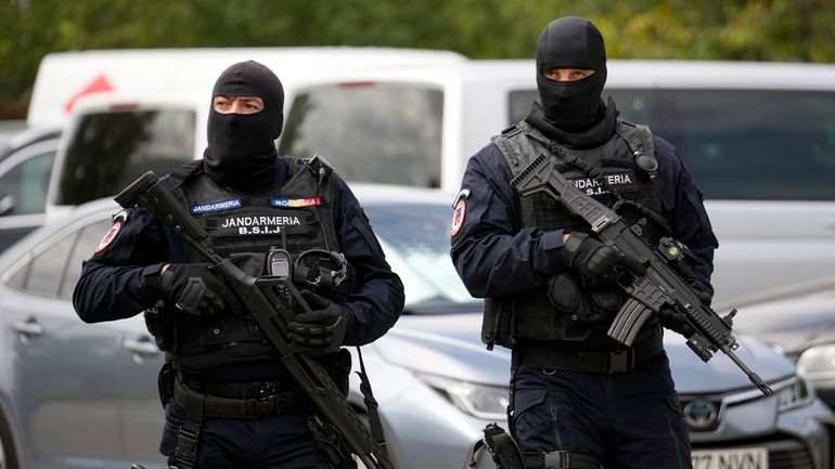 Armed gendarmes wearing balaclavas walk outside the residence of Andrew...